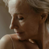 Close-up of a mature woman with short hair, wearing a light-colored top.