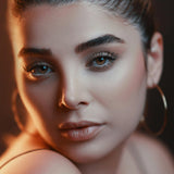 Close-up of a woman with hoop earrings against a dark background