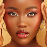 Close-up of a woman with makeup and jewelry on a beige background