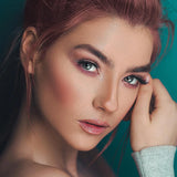 Close-up of a woman with makeup against a teal background