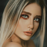 Close-up of a person with blonde hair and makeup against a dark background