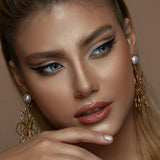 Close-up of a woman with makeup and jewelry on a neutral background
